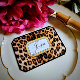 Close-up of a leopard-print place card, a guest's name in script inside its gold-framed cartouche