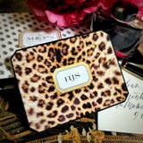 A leopard-print note card with a three-letter monogram in serif capitals, on a hand-lettered envelope