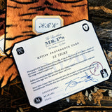 A clipped-corner card printed "MÉTIER PROVENANCE CARD" with the tiger design's story, signed in blue ink by both cofounders, over a tiger-print note card with a two- to three-letter monogram in script, on a chinoiserie lacquer table