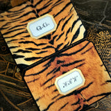 Two tiger-print note cards, one monogram in serif capitals and one in script, on a chinoiserie lacquer table