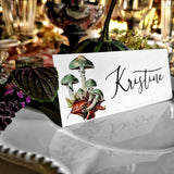 The Punctilious Mr. P's Place Card Co. 'Verdigris Mushrooms' laydown custom place card on top of linen napkin with bamboo cutlery and a red color blocked tablecloth