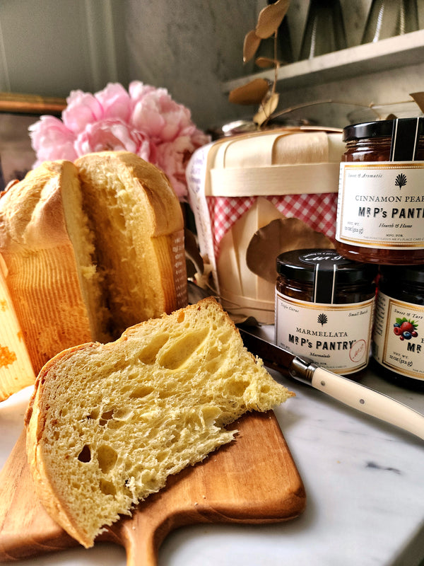 Slice of panettone on a wooden board with jars labeled 'Mr P's Pantry' in the background.