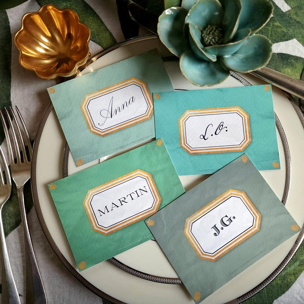 showing all 4 of The Punctilious Mr. P's place card co. 'Envoy- Jardin' shades of greens laydown event size custom place cards on printed tablecloth tablescape with fresh flowers and vintage silver cutlery