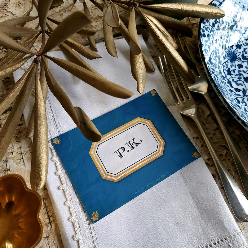 The Punctilious Mr. P's place card co. 'Envoy- Marine' shades of blues laydown event size custom place cards on printed tablecloth tablescape with fresh flowers and vintage silver cutlery