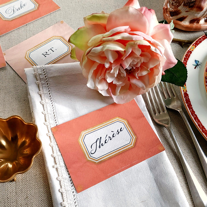 The Punctilious Mr. P's place card co. 'Envoy- Marine' shades of oranges laydown event size custom place cards on printed tablecloth tablescape with fresh flowers and vintage silver cutlery