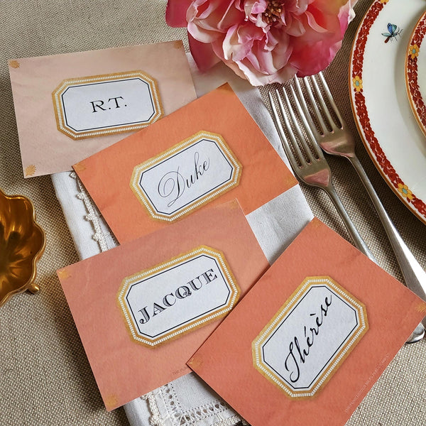 showing all 4 of The Punctilious Mr. P's place card co. 'Envoy- Melon' shades of oranges laydown event size custom place cards on printed tablecloth tablescape with fresh flowers and vintage silver cutlery
