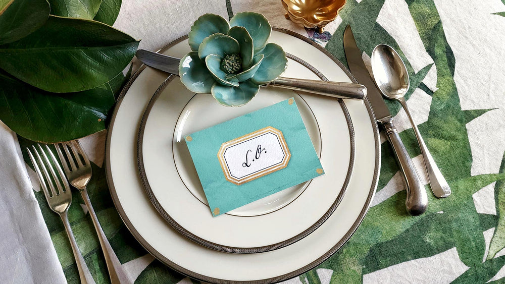 The Punctilious Mr. P's place card co. 'Envoy- Jardin' shades of greens laydown event size custom place cards on printed tablecloth tablescape with fresh flowers and vintage silver cutlery