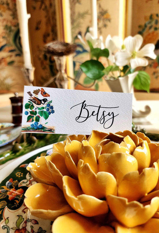 The Punctilious Mr. P's Place Card Co. Birds, Berries, and Butterflies Place Card with the name Betsy on a yellow Ceramic Blossom 