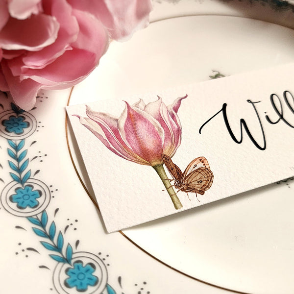 detail of The Punctilious Mr. P's place card co. 'Blossoms' laydown size custom place cards on black and gold china tablescape with fresh flowers and vintage silver cutlery