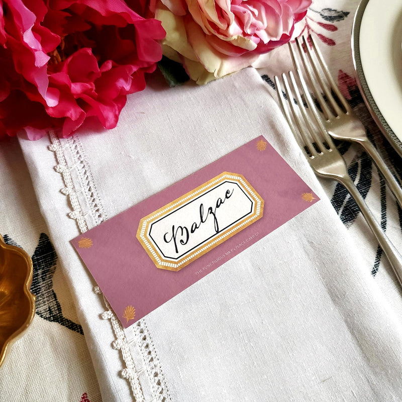 The Punctilious Mr. P's place card co. 'Envoy- Aubergine' shaded of purples laydown size custom place cards on printed tablecloth tablescape with fresh flowers and vintage silver cutlery showing the Old Kinderhook font