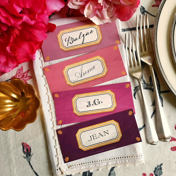 showing all 4 hues of The Punctilious Mr. P's place card co. 'Envoy- Aubergine' shaded of purples laydown size custom place cards on printed tablecloth tablescape with fresh flowers and vintage silver cutlery