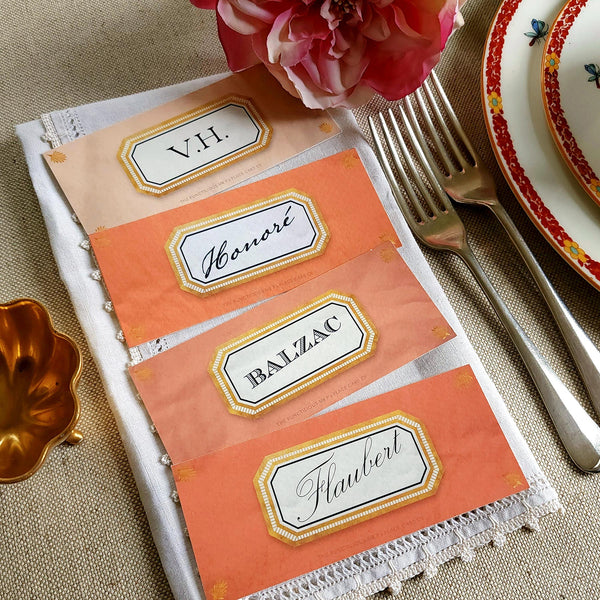 showing all 4 hues of The Punctilious Mr. P's place card co. 'Envoy- Melon' shades of oranges laydown size custom place cards on printed tablecloth tablescape with fresh flowers and vintage silver cutlery