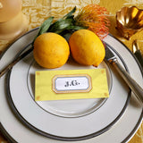 The Punctilious Mr. P's place card co. 'Envoy- Soleil' shades of yellows laydown size custom place cards on printed tablecloth tablescape with fresh flowers and vintage silver cutlery