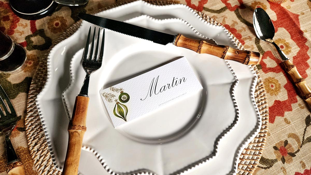 mr. p's mid century baubles laydown place card on white dinner plate with bamboo cutlery and colorful suzani tablecloth