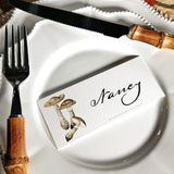 The Punctilious Mr. P's "Pantherina Mushrooms" laydown illustrated place cards on a white dinner plate with bamboo cutlery