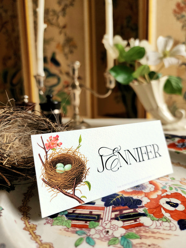 Robins Egg place card with a bird's nest and floral design on a table setting.