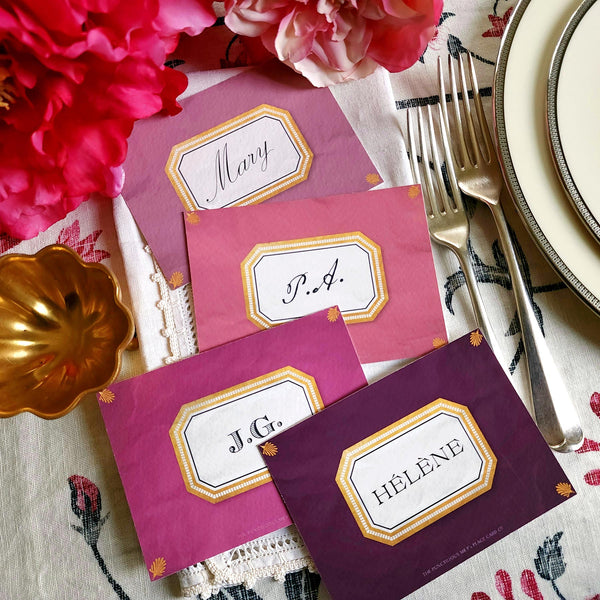 showing all 4 hues of The Punctilious Mr. P's place card co. 'Envoy- Aubergine' shaded of purples laydown size custom place cards on printed tablecloth tablescape with fresh flowers and vintage silver cutlery