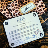 A clipped-corner card printed "MÉTIER PROVENANCE CARD" with the leopard design's story, signed in blue ink by both cofounders, over leopard-print note cards reading "Merci" in script on a chinoiserie lacquer table