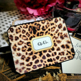 A leopard-print note card with a three-letter monogram in serif capitals, beside a crystal ink bottle