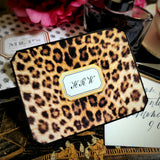 A leopard-print note card with a three-letter monogram in script, against the anthemion-print folio and a hand-lettered envelope