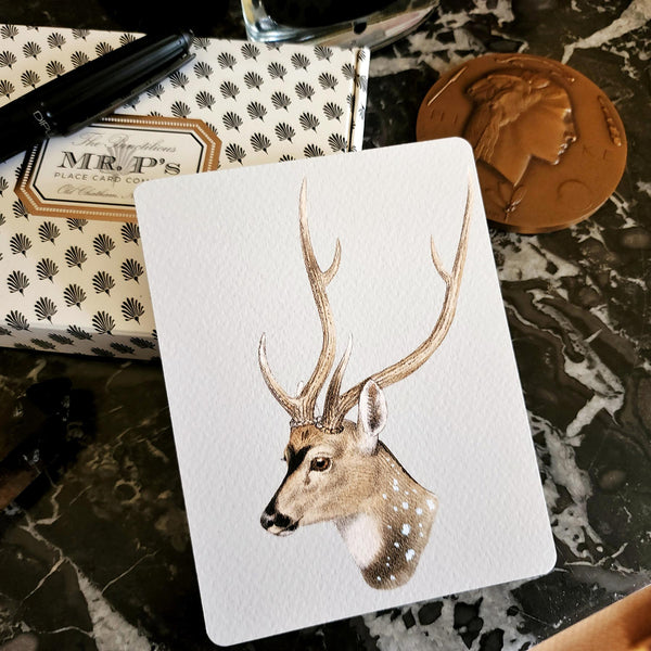 The Punctilious Mr. P's Place Card Co. 'Deer' custom note card pack on a black marble table with signature anthemion note card box and fountain pen and bronze medallion in the background