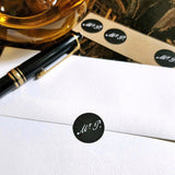 view of The Punctilious Mr. P's round black signature sticker on the back of an envelope with bottle of ink and montblanc fountain pen