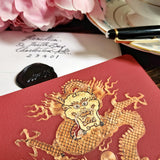 detail of The Punctilious Mr. P's Place Card Co. 'Radiant Dragon-Cinnabar' custom note card pack with a montblanc fountain pen on a chinoiserie table with cup of tea and large beautiful peony flower