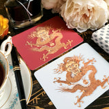 The Punctilious Mr. P's Place Card Co. 'Radiant Dragon' custom note card pack in both white and cinnabar backgrounds with a montblanc fountain pen on a chinoiserie table with cup of tea and large beautiful peony flower