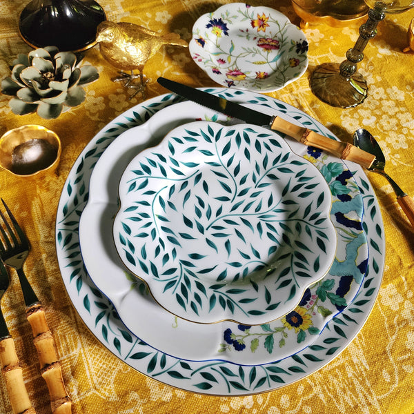 Decorative table setting with patterned plates and cutlery on a gold tablecloth.