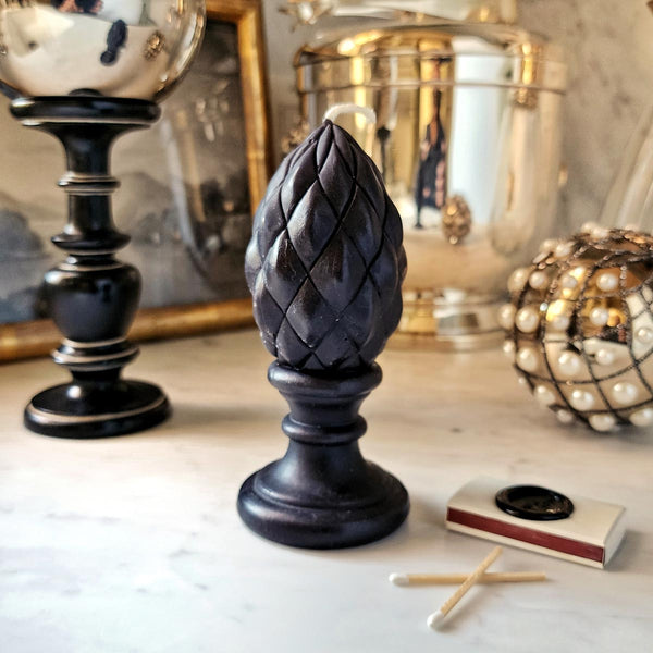 The Punctilious Mr. P's black finial candle on a white marble table with a box of matches