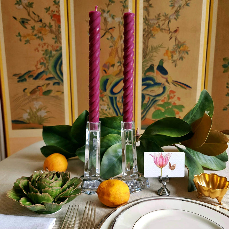 featuring The Punctilious Mr. P's Place Card Co. rope taper candle in Aubergine on a simple tablescape with large magnolia leaves, place card, ceramic flowers against a chinoiserie screen as a backdrop