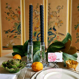 featuring The Punctilious Mr. P's Place Card Co. rope taper candle in black on a simple tablescape with large magnolia leaves, place card, ceramic flowers against a chinoiserie screen as a backdrop