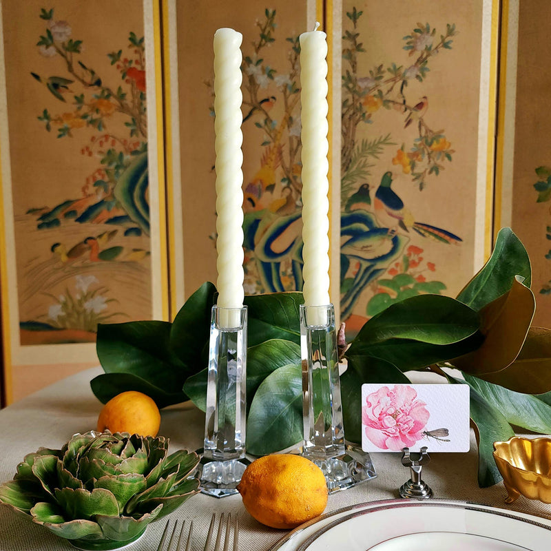 featuring The Punctilious Mr. P's Place Card Co. rope taper candle in creme on a simple tablescape with large magnolia leaves, place card, ceramic flowers against a chinoiserie screen as a backdrop
