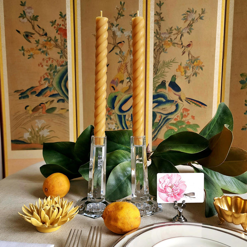 featuring The Punctilious Mr. P's Place Card Co. rope taper candle in natural on a simple tablescape with large magnolia leaves, place card, ceramic flowers against a chinoiserie screen as a backdrop