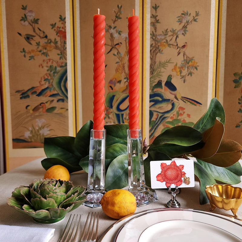 featuring The Punctilious Mr. P's Place Card Co. rope taper candle in persimmon on a simple tablescape with large magnolia leaves, place card, ceramic flowers against a chinoiserie screen as a backdrop