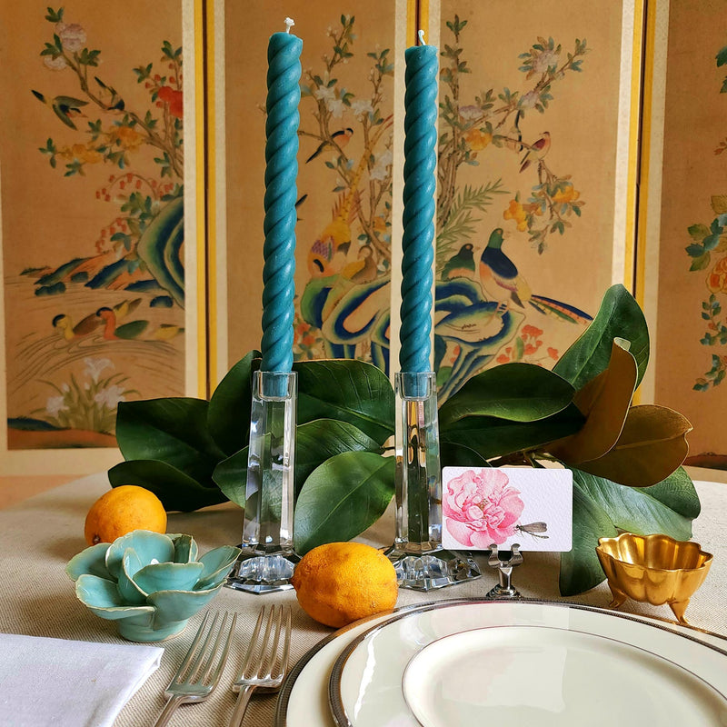 featuring The Punctilious Mr. P's Place Card Co. rope taper candle in teal on a simple tablescape with large magnolia leaves, place card, ceramic flowers against a chinoiserie screen as a backdrop