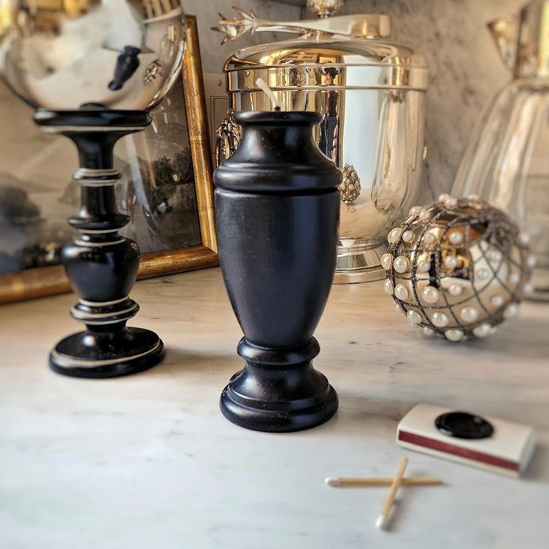 the punctilious Mr. P's black urn beeswax candle on marble tabletop 