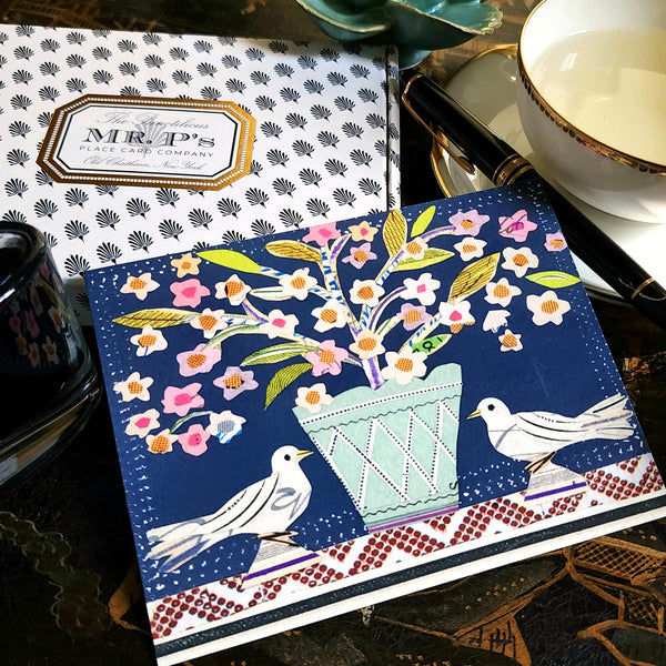 The Punctilious Mr. P x Sarah V Battle "Doves & Swans" fine note card set featuring collage reproductions of her original artwork, on chinoiserie table with Mr. P's I conic black and white anthemion print. montblanc fountain pen resting by  