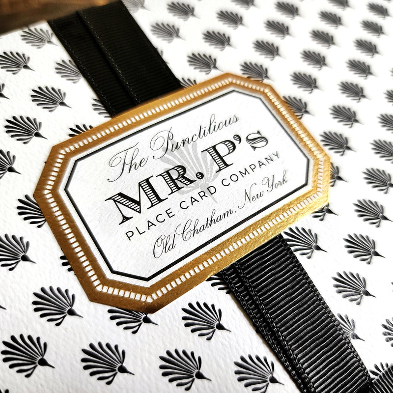 detail of Mr. P's Pantry's Jam Trio Gift Set packaging wrapped in signature anthemion pattern with gold foil label and black grosgrain ribbon