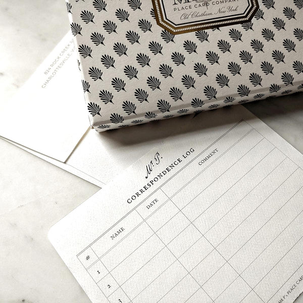 the punctilious Mr. P's Place Card Co. correspondence log to track your 8 custom note cards, on a marble table with the their signature anthemion printed note card packaging.
