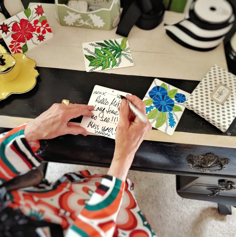 Marian Mcevoy hold a custom note card in her hands at her black and white stripe writing desk