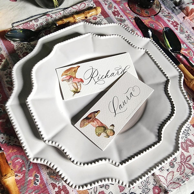 The Punctilious Mr. P's "Russula Mushrooms" laydown illustrated place cards on a white dinner plate with bamboo cutlery
