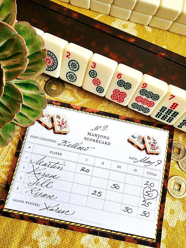 Mr. P's Mahjong scorecard, and coins on a decorative table with a ceramic blossom.