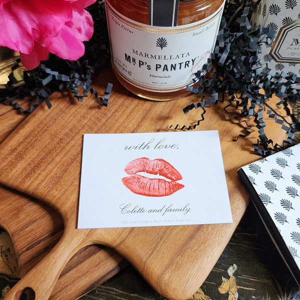 The Punctilious Mr. P's Place Card Co. "Kisses" Custom Gift Notes on a chinoiserie table with marmalade jam, cutting board and fresh flowers