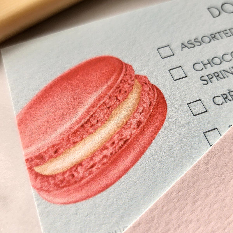 detail of The Punctilious Mr. P's Place Card Co. Macaroon and Cookies Dessert cards on a marble table with peony and and a dish with stacked macaroons