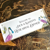 The Punctilious Mr. P's Place Card Co. "Spoonbills Custom Illustrated Signage" in a acrylic book that welcomes wedding guests to a rehearsal dinner