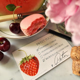 The Punctilious Mr. P's Place Card Co. Strawberries Dessert cards on a marble table with peony and a dish with a slice of watermelon and macaroon