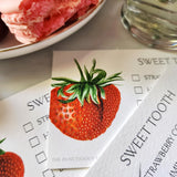showing details of The Punctilious Mr. P's Place Card Co. Strawberries Dessert cards on a marble table with peony and a dish with a slice of watermelon and macaroon