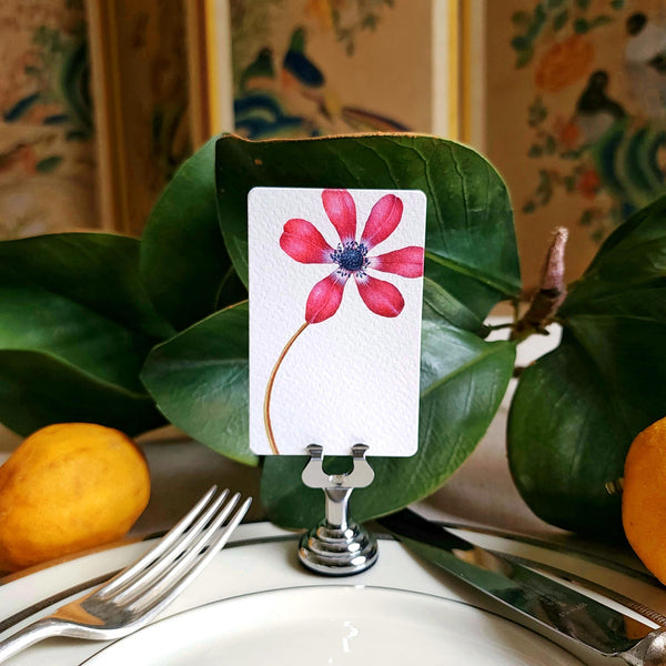 The Punctilious mr. P's Pace Card Co. "anemones" custom place card on a silver place card holder with magnolia leaves and lemons in the background against a chinoiserie screen