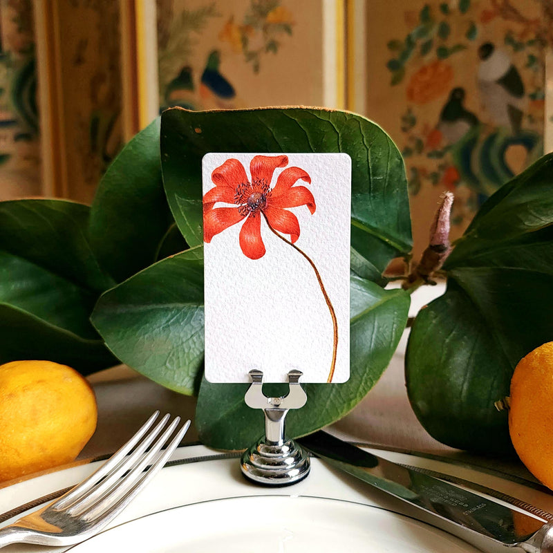 The Punctilious mr. P's Pace Card Co. "anemones" custom place card on a silver place card holder with magnolia leaves and lemons in the background against a chinoiserie screen